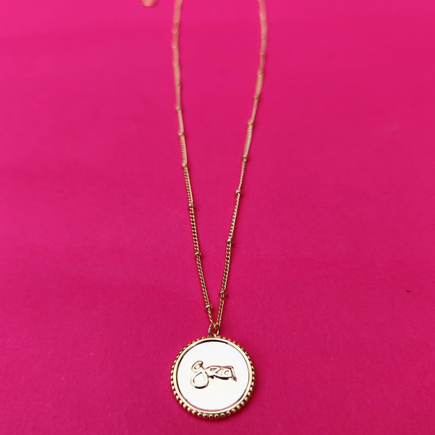 Grá Medallion Gold Necklace on Pink Background